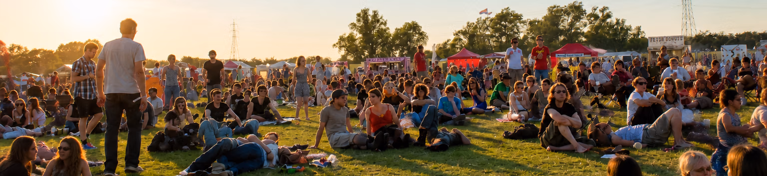 LodeStar Festival in Cambridgeshire, field with festival-goers sitting and walking around listening to music and enjoying Aspall's cider and Calvors finest English Pilsner Lager in the summer sun.